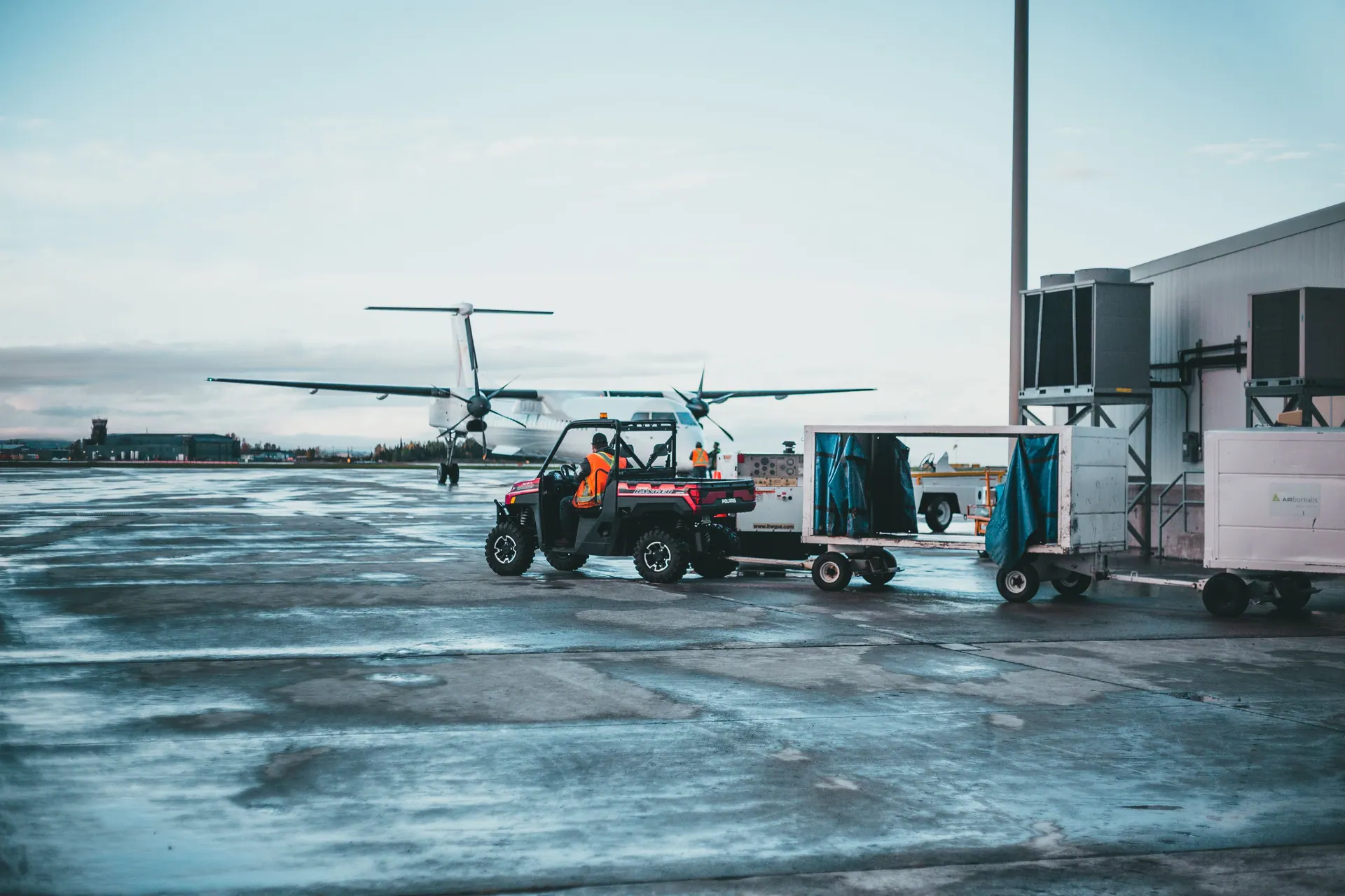 Vorfeld am Flughafen mit Gepäckschlepper, Bodenpersonal und Flugzeug
