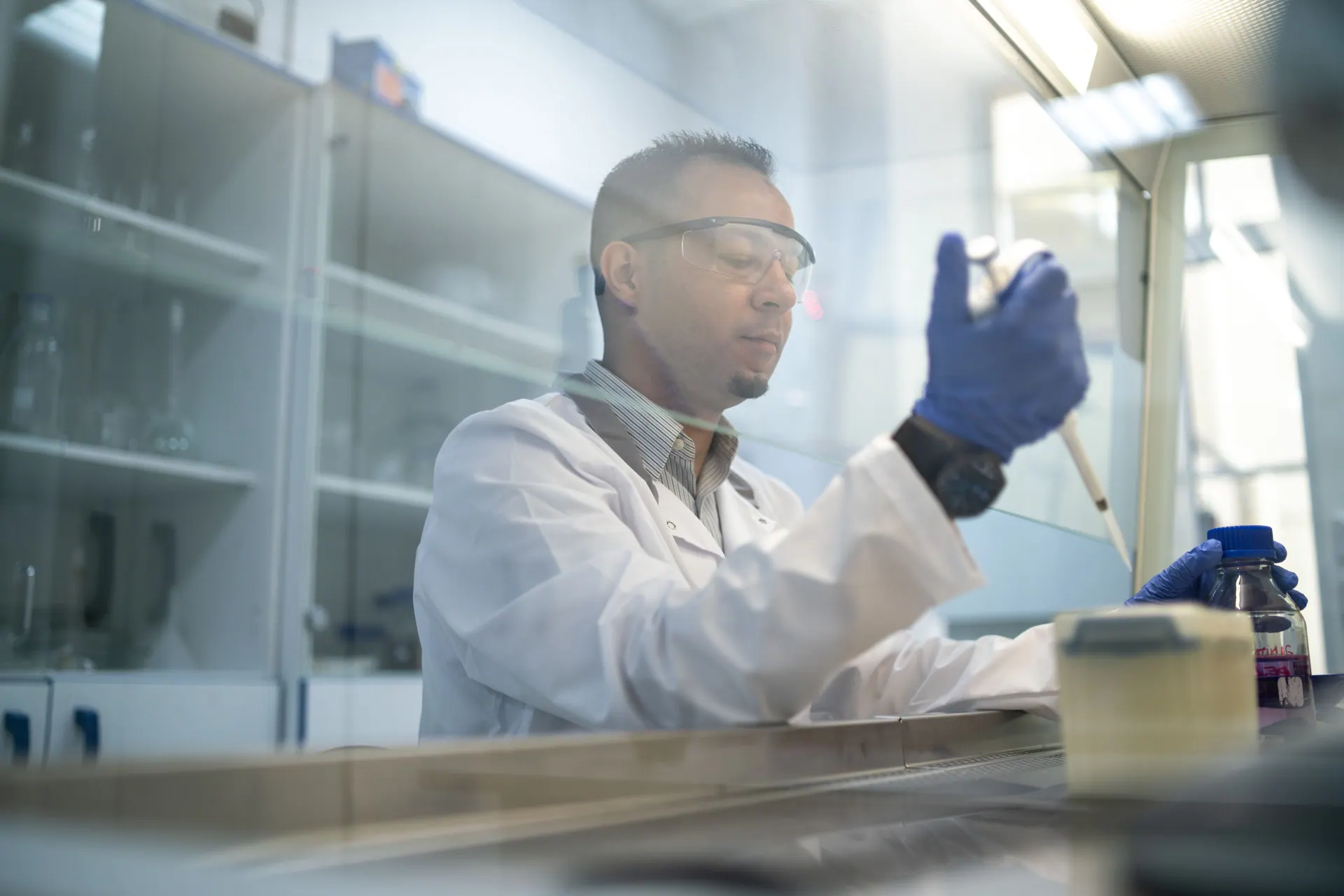 Wissenschaftler mit Schutzbrille arbeitet an einer Laborbank